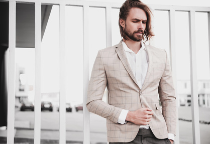 Portrait of sexy handsome fashion male model man dressed in elegant beige checkered suit .posing on the street background_152271111_XS