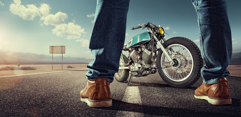 Sport. Biker standing near the motorcycle on an empty road at sunny day. Close view on legs_92850548_XS